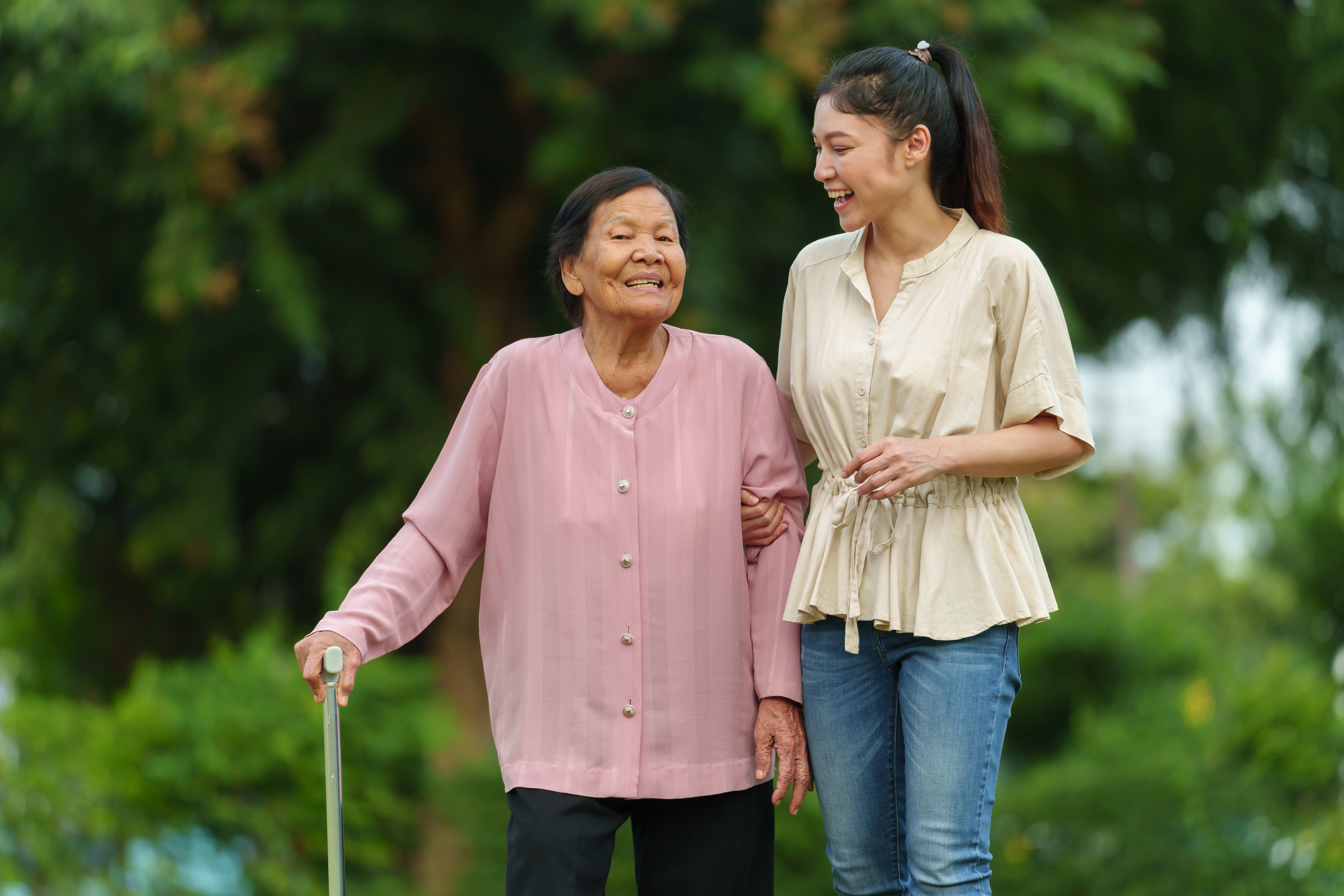 a smiling elder woman with a cane and her NEMT driver